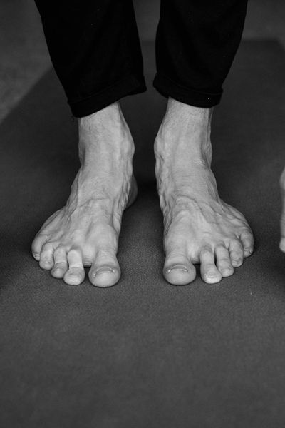 Close-up on hands and feet in a focused yoga pose, showing control and stability.